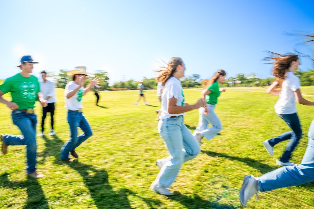 4-H members running through an open grassy lawn. 