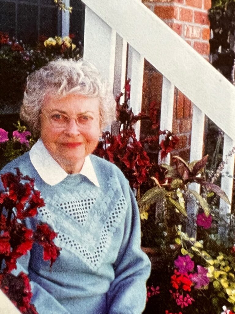 Barbara sitting on here front steps next to her home garden.
