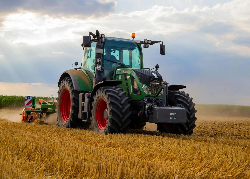 A large tractor drives through an agricultural field