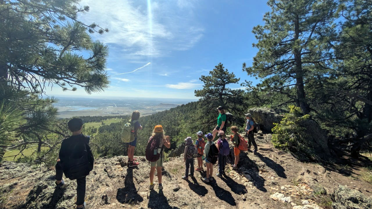 Eight youths and two adults look on from an overlook into view of Jefferson County as part of ENOR Environmental Discovery Camp.