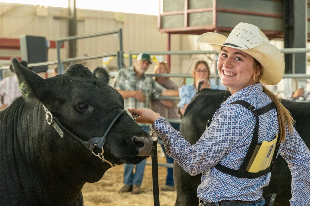 A member of Jefferson County 4-H shows off her cattle and smiles at the camera.