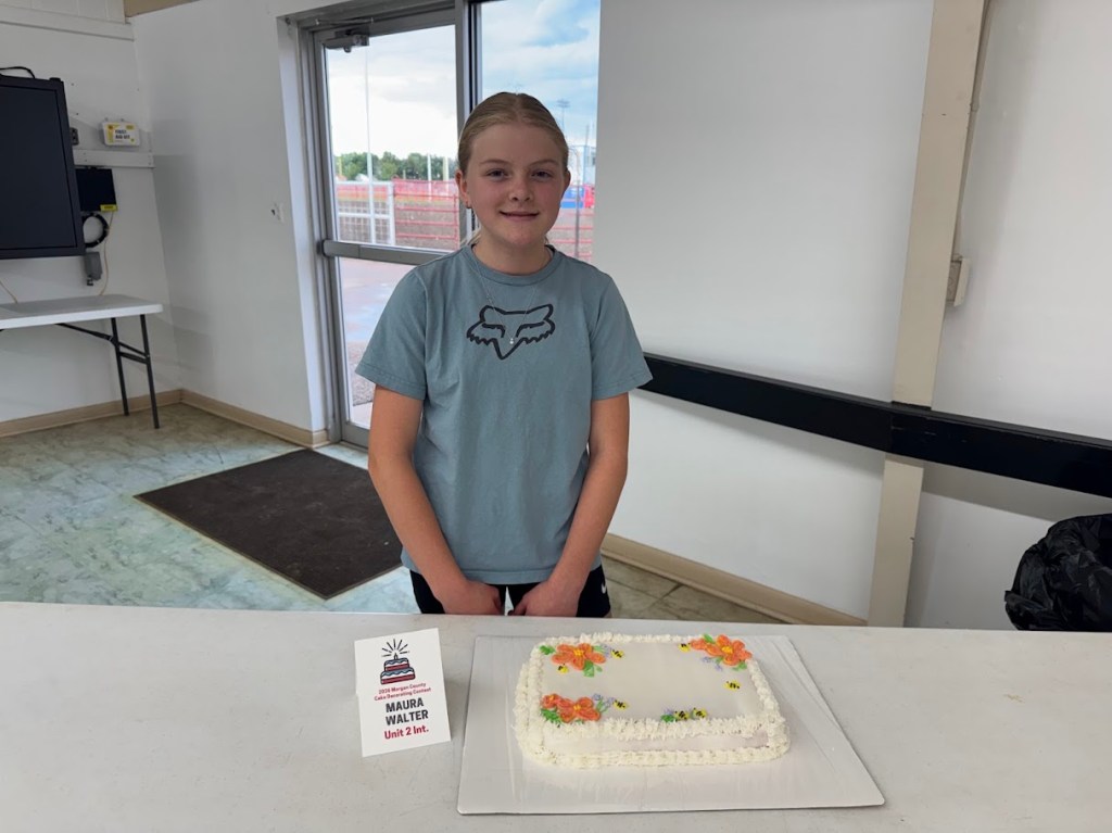Maura Walter with her white frosted cake with bumble bees and orange flower decorations