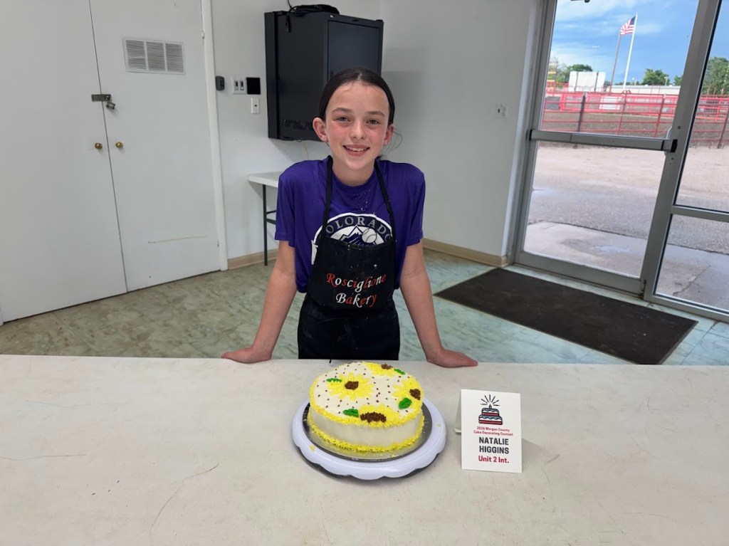 Natalie Higgins with her white frosted cake with sunflowers and sunflower seed decorations