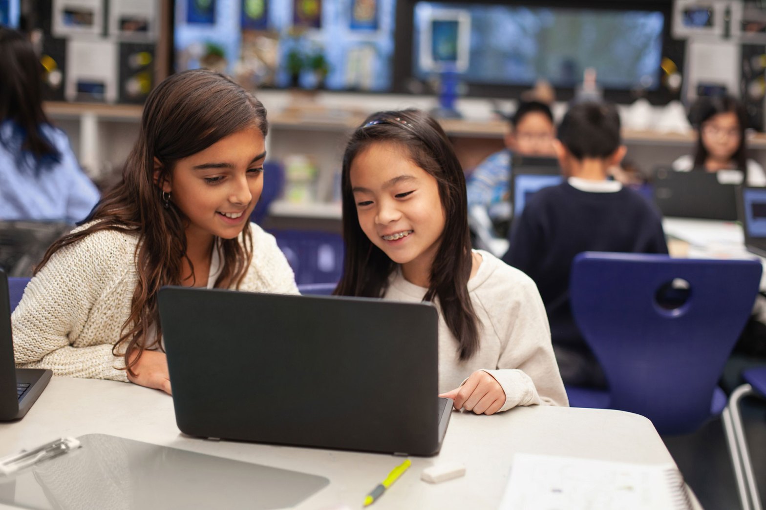 Two girls work together at a laptop computer