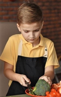 Young child cutting vegetables