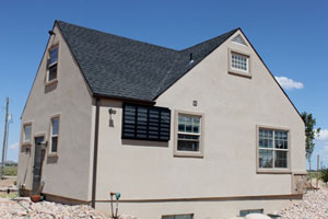An image of a single-family home with a wall mounted solar hot air collector attached to the outside wall.
