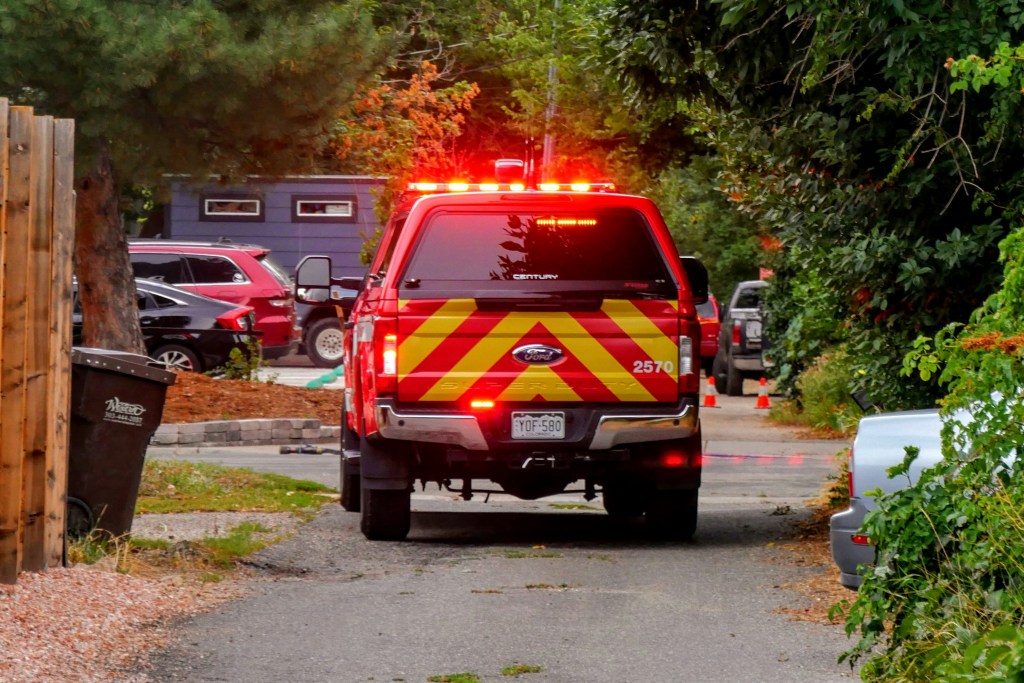 Emergency vehicle with flashing lights parked in a narrow residential alley.
