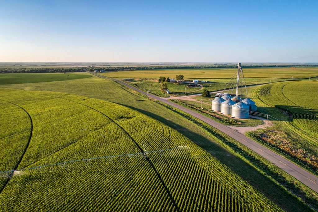 Aerial view of corn field with sprinkler, silo, and farm buildings in eastern Colorado