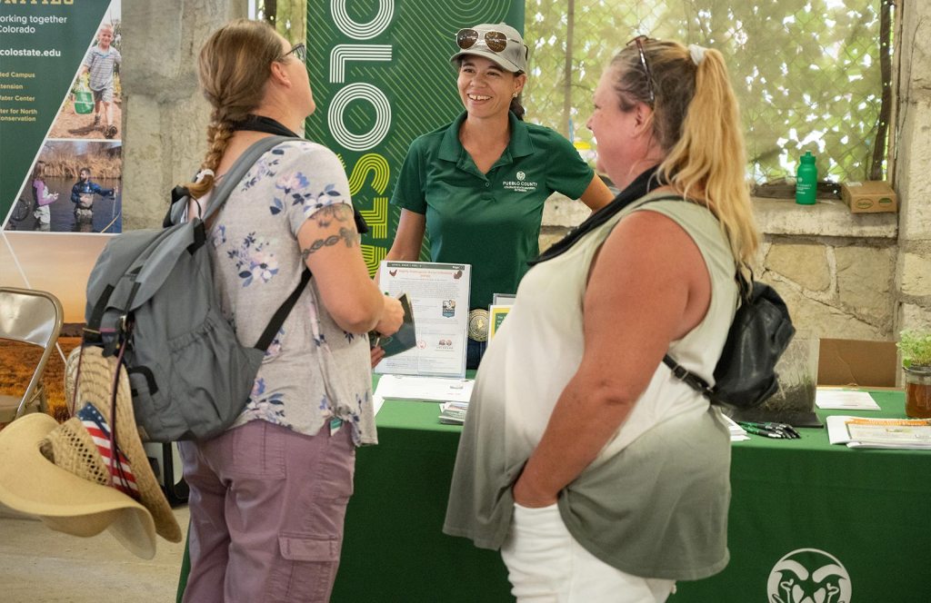 People talk at a CSU booth at an event