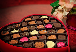 Red heart box filled with an array of chocolates of all different colors and flavors.