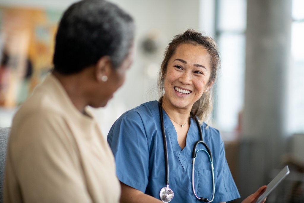 A nurse smiles while talking with a patient during a consultation.