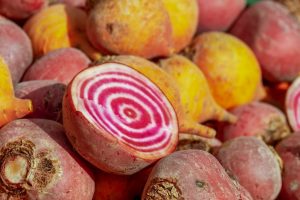 Cut raw beet in a pile of beets. The pink and white rings inside are visible.