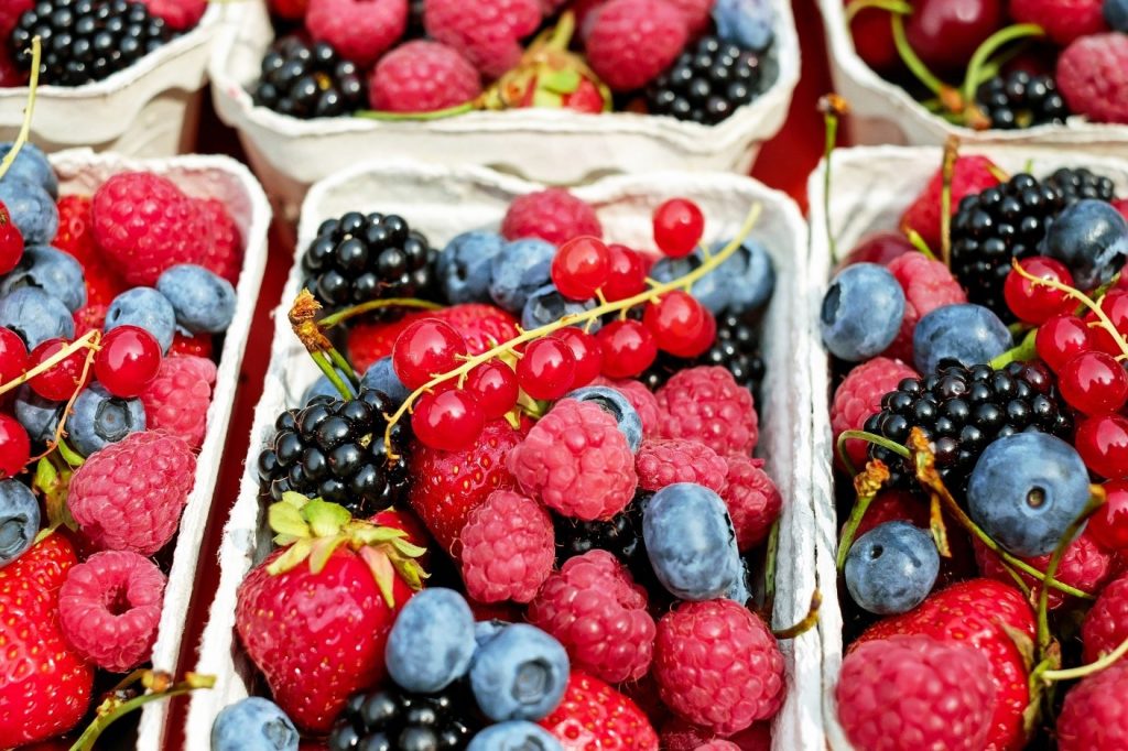 Mixed berries, including strawberries, black berries, raspberries and blueberries in a small carton. 
