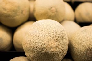 Raw, whole cantaloupe stacked on top of each other. 