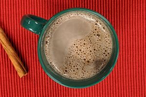 hot chocolate in a mug next to a cinnamon stick
