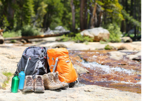 two backpacks and boots sit next to a mountain stream.
