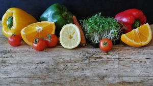 Fruits and vegetables sitting on a greyed wooden table. 