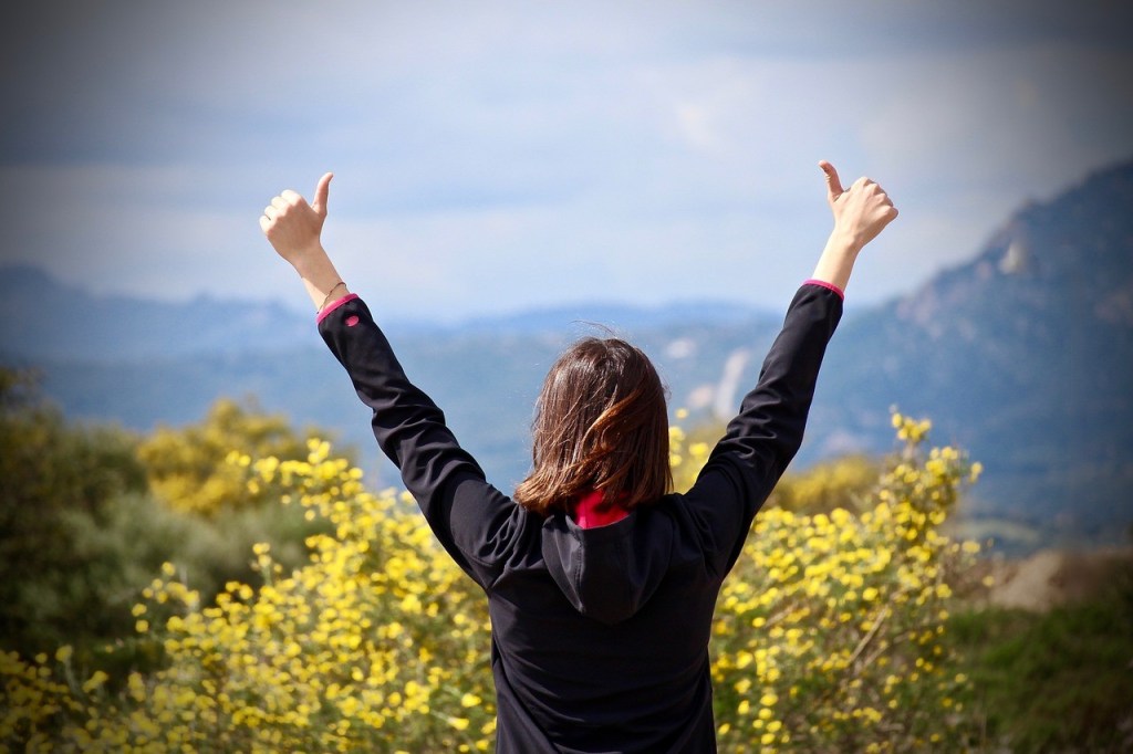 Woman giving 2 thumbs up in a mountainous nature environment demonstrating her flow.