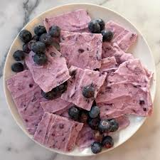 Pieces of blueberry yogurt bark topped with fresh blueberries on a white plate.