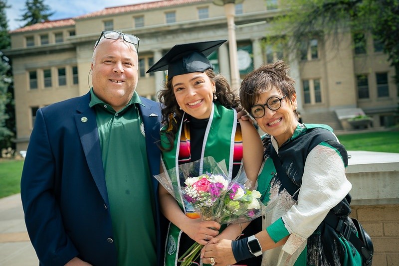 A CSU alumna stands with her parents after graduation