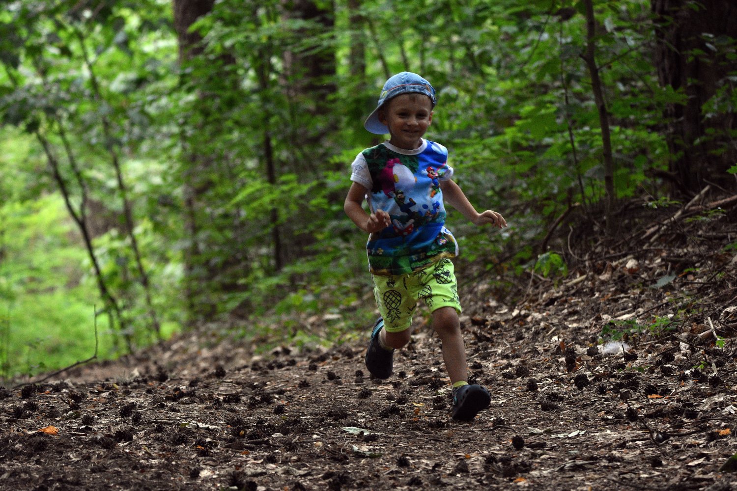 A child runs along a wooded trail surrounded by trees and forest vegetation.